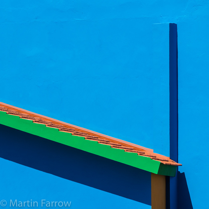 Blue-Green-and-Orange 
 Blue wall with green edged roof 
 Keywords: Canaries, Gran Canaria, blue, bright, building, colour, green, orange, roof, shadow, stark, wall