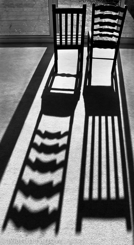 Sharing 
 Chairs with shadows swapped 
 Keywords: chairs, shadows, sun,strange,wrong,quirky