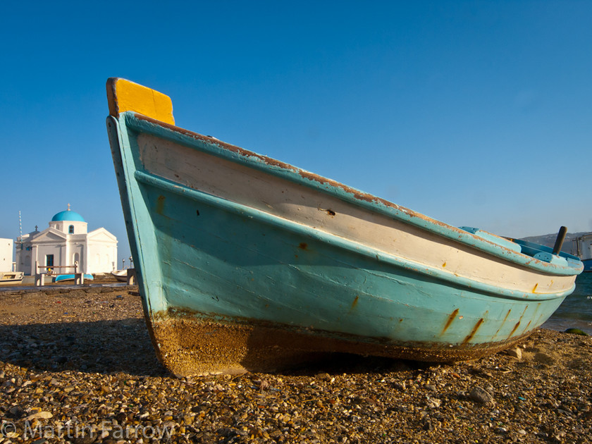 Beached 
 Boat on shore with church in background 
 Keywords: Chora, Greece, Mykonos, morning,boat,beach,shore,blue,church,sky