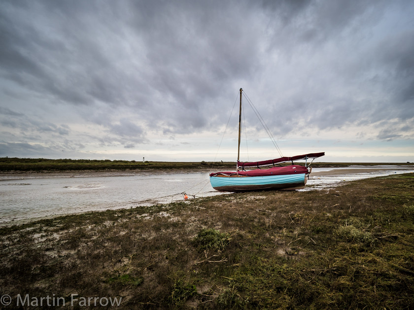 Up-The-Creek 
 Boat aground at low tide 
 Keywords: Blakeney, Norfolk, boats, coast, estury, mud, reeds, sea, tidal, water, winter,boat,blue,ashore,aground,clouds