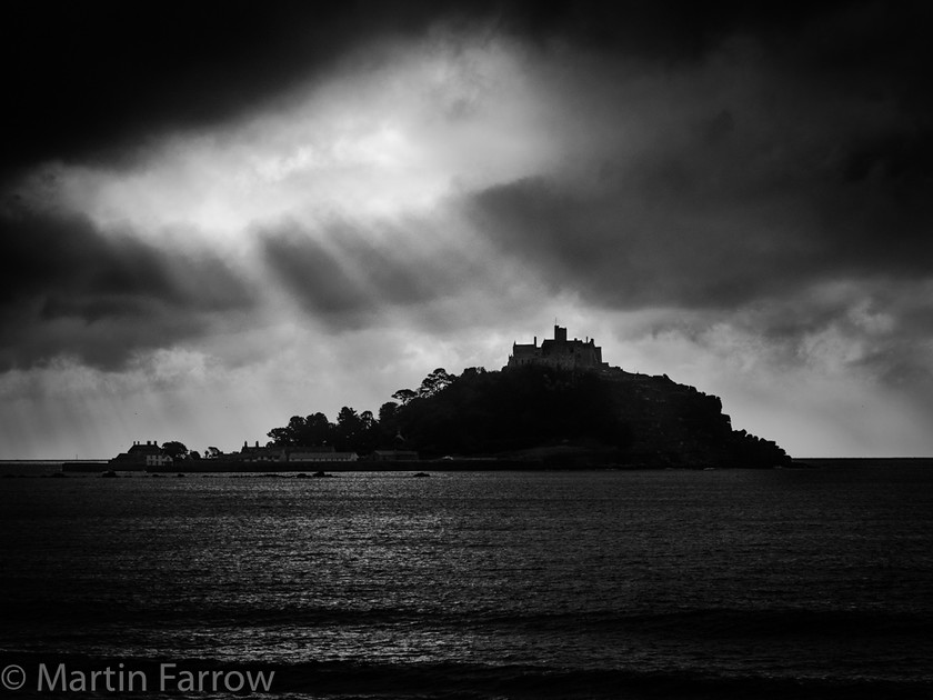 Heavenly-Spotlight 
 St Michaels Mount in Cornwall back lit by shafts of light from stormy clouds, monochrome 
 Keywords: Cornwall, St Ives.coast, St Michaels Mount, back lit, cloud, clouds, lenticular reys, light, ocean, sea, shaft, shore, water