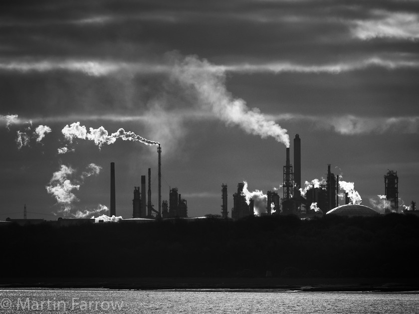 Fawley 
 Silhouette of refinery with steaming shimneys backlit by evening sun, monochrome 
 Keywords: back light, beach, contrast, evening, fFawley, monochrome, refinery, silhouette, smoke, steam, water, winter