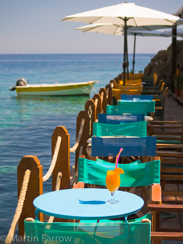 Orange-Coctail 
 `Orange cocktail on sea front bar table 
 Keywords: Crete, Greece,sea,shore,bar,table,chair,orange,drink,cocktail,boat,moored